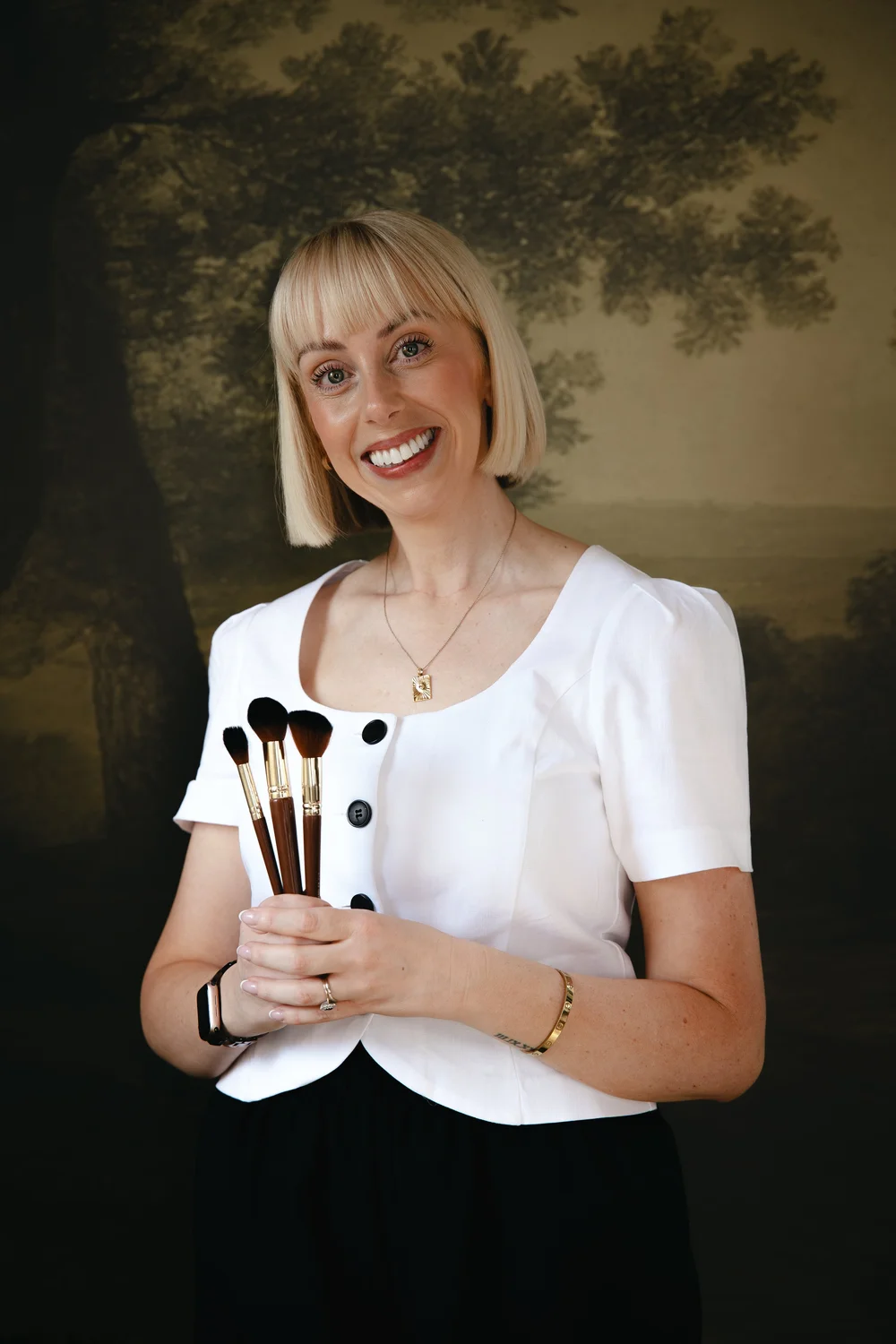 Becci Young holding makeup brushes in the studio