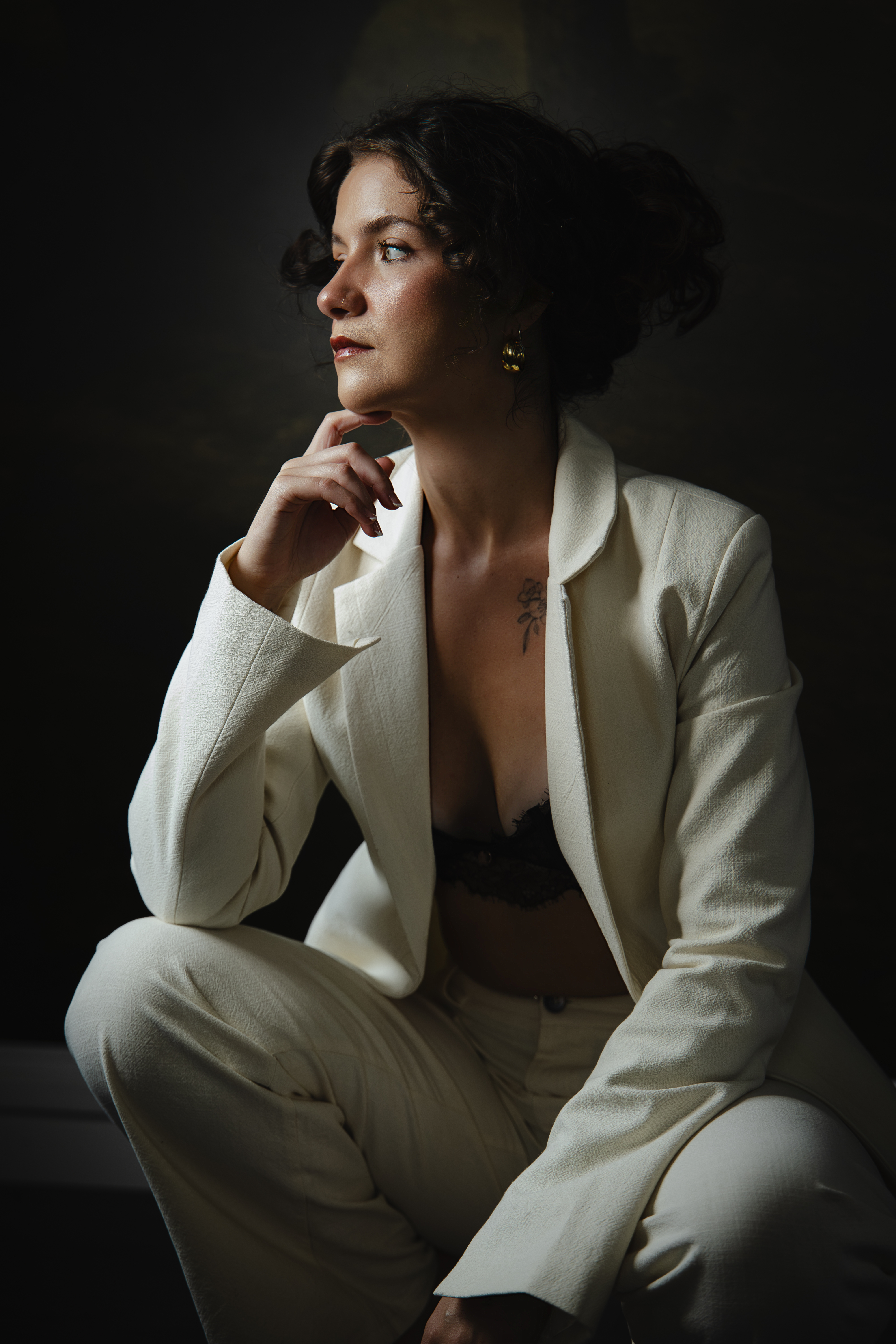 Jess seated in a white suit, looking towards the window