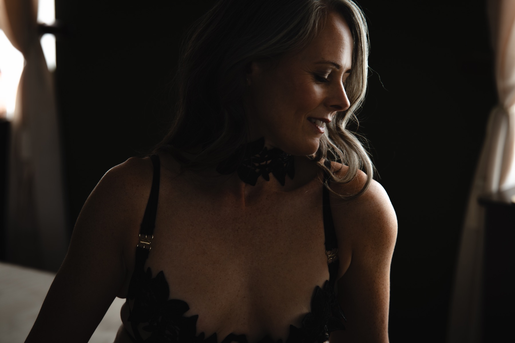 A woman smiling in profile in gentle window light